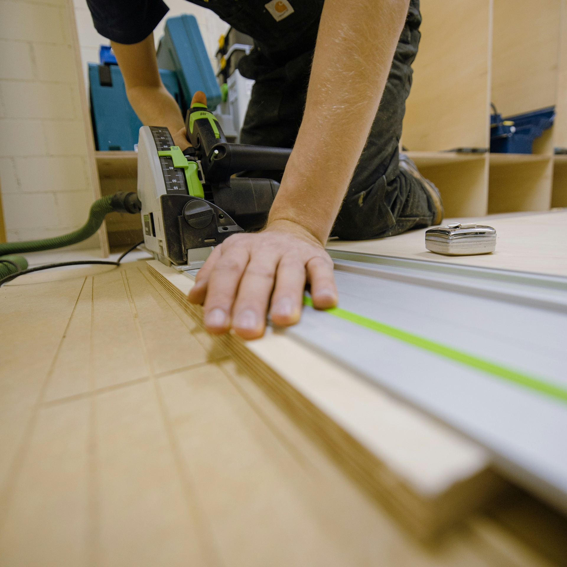 An independent handyman precisely measuring and cutting wood with a track saw